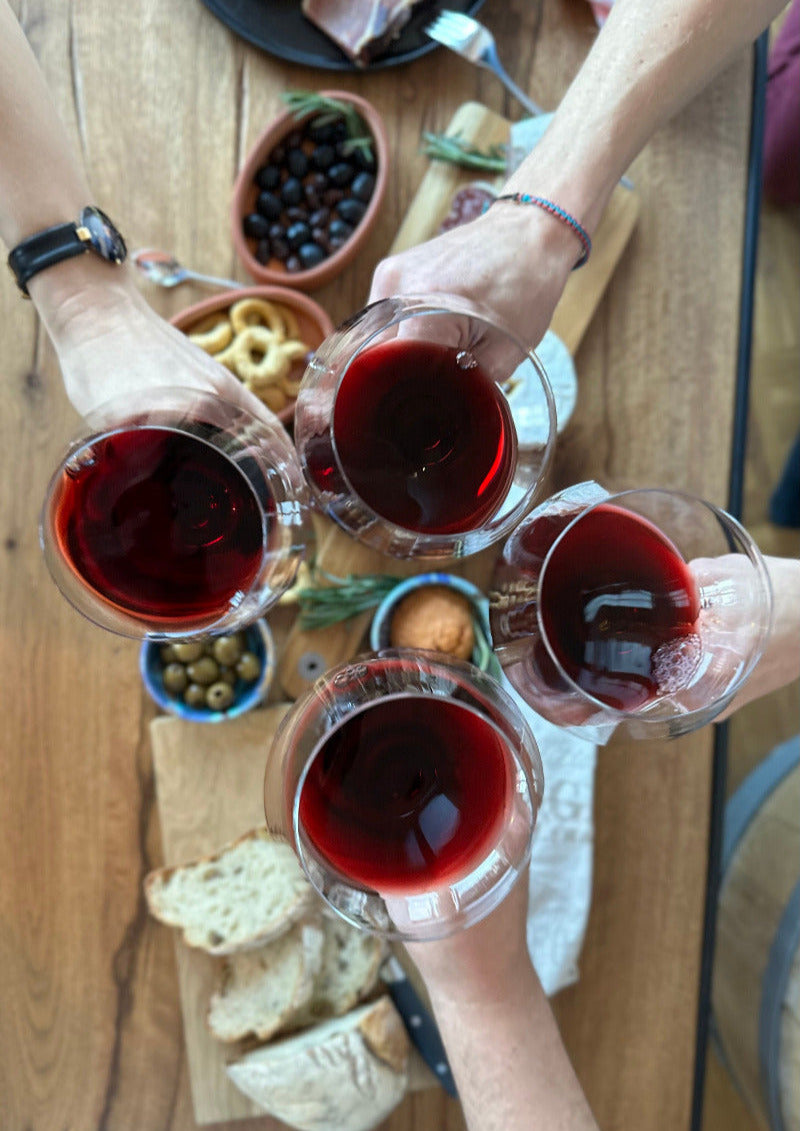 CORE Wines stossen mit einem Glas Wein an mit kleinem Apéro im Hintergrund als Sinnbild für die Weindegustation